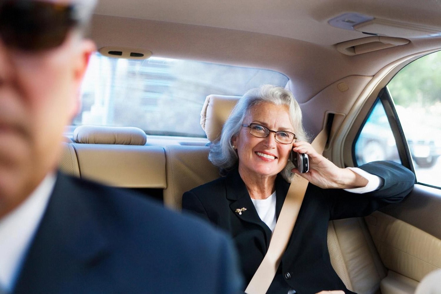 Businesswoman on a phone call in the back seat of a chauffeur-driven car in Dubai