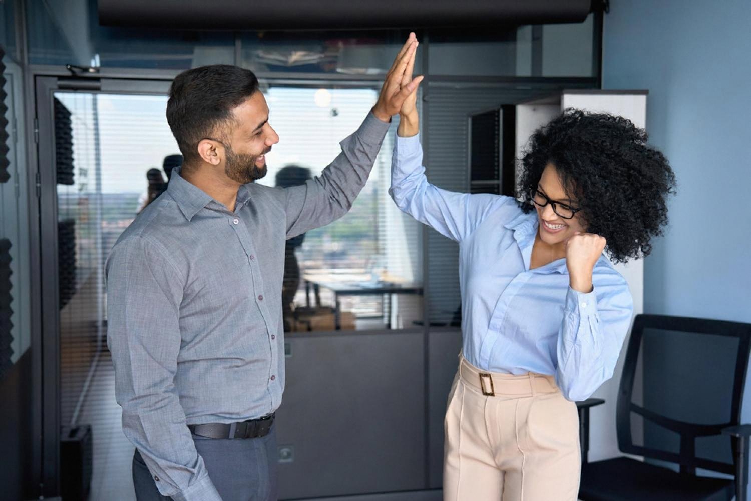 Colleagues celebrating a win with a high five in a UAE workplace