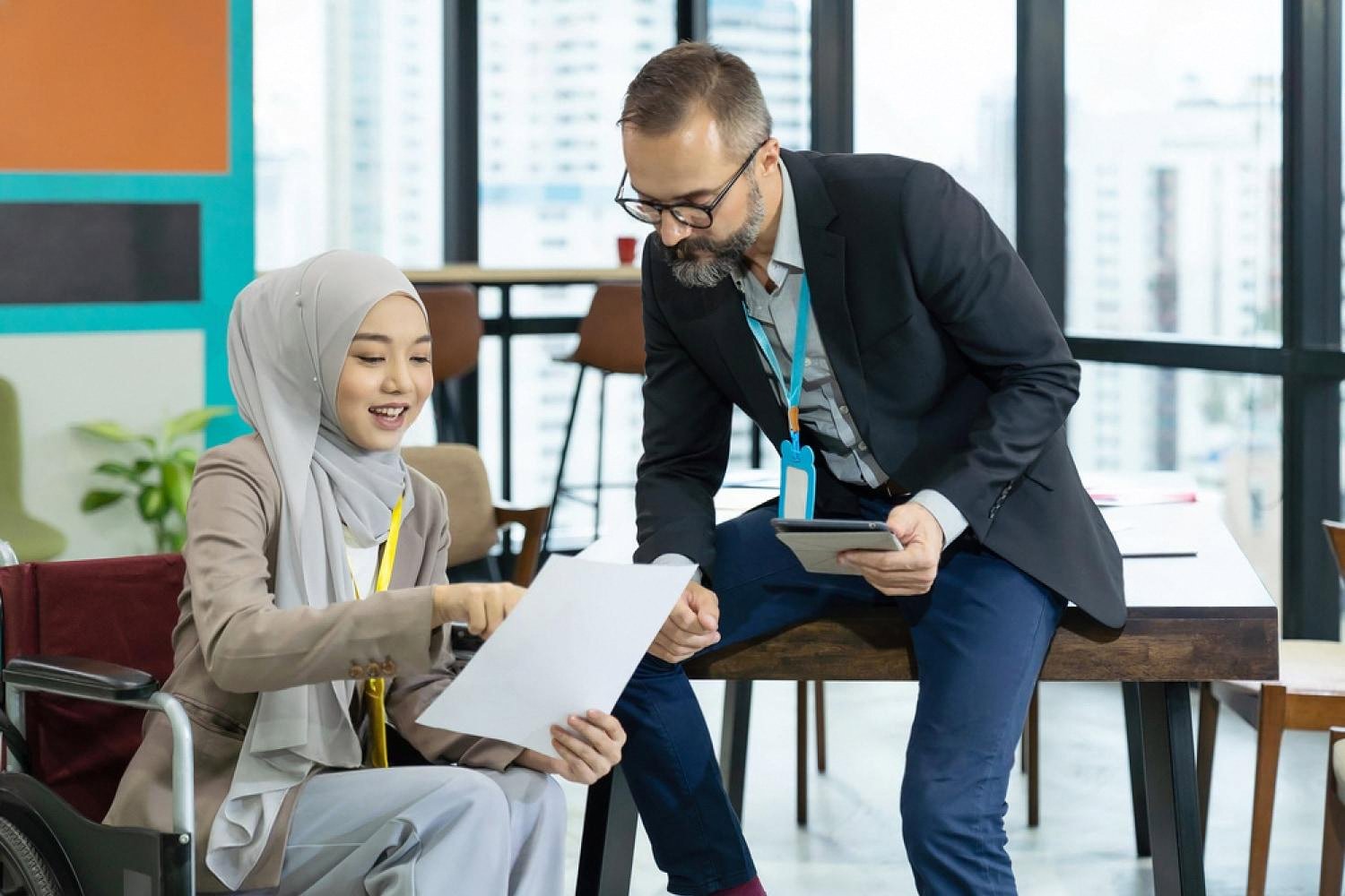 Two coworkers reviewing a document together in a modern Dubai office